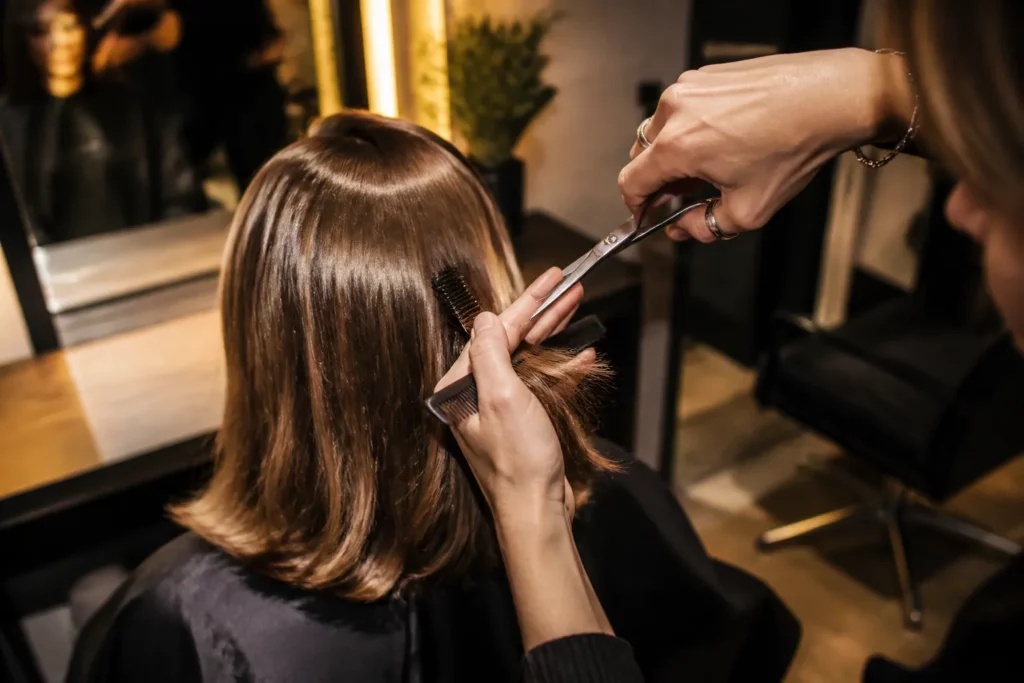 kapper knipt nauwkeurig de punten van halflang haar bij in een warme, moderne kapsalon